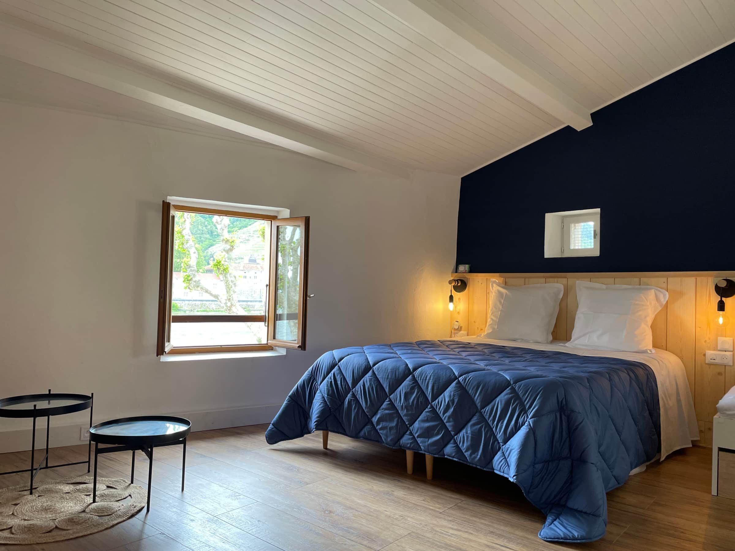 Chambre sous les combles avec fenêtre ouverte sur les coteaux de vignes et le château de Tournon