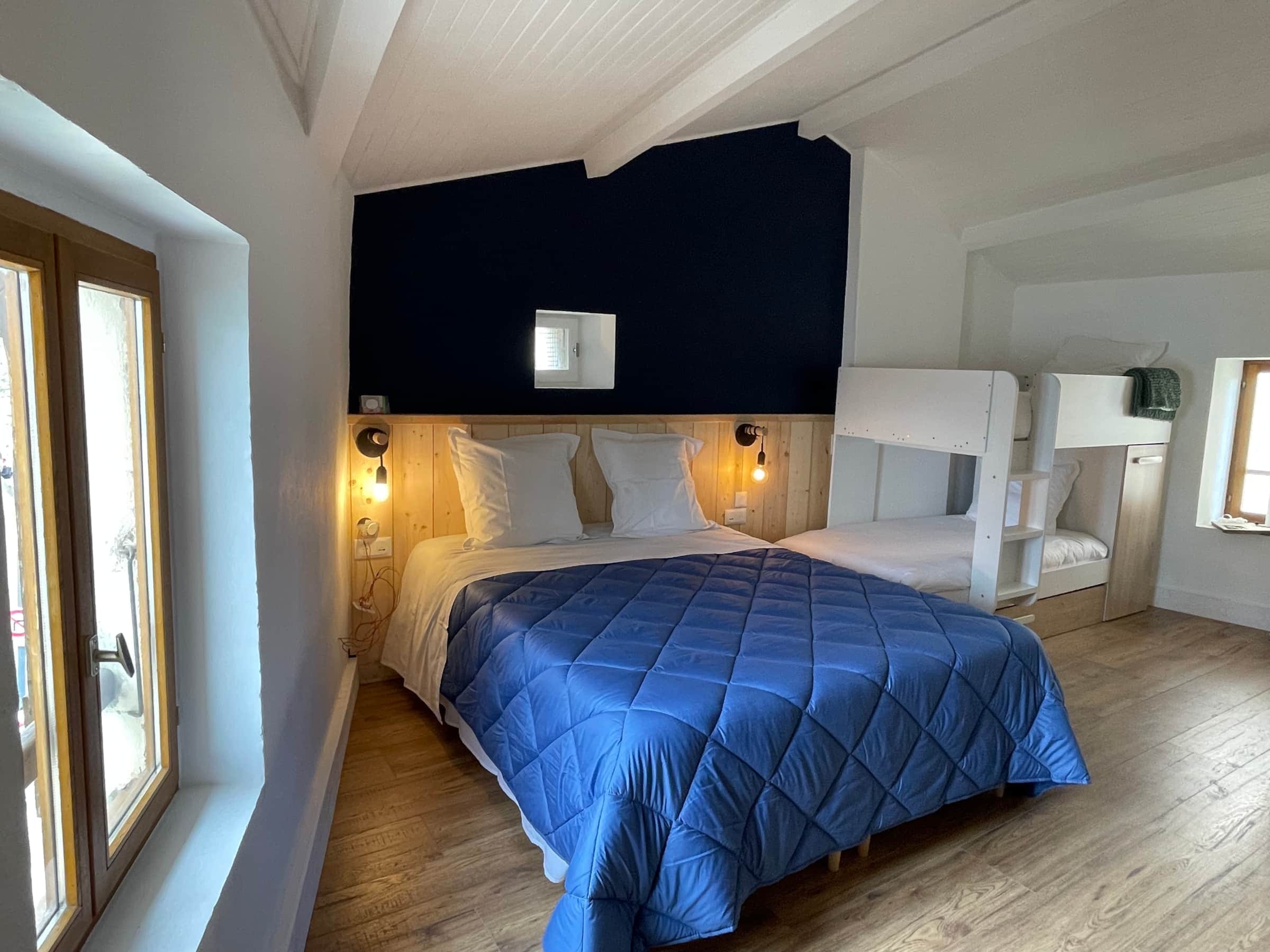 Chambre familiale avec lit queen size et lits superposés blancs, idéale pour les enfants