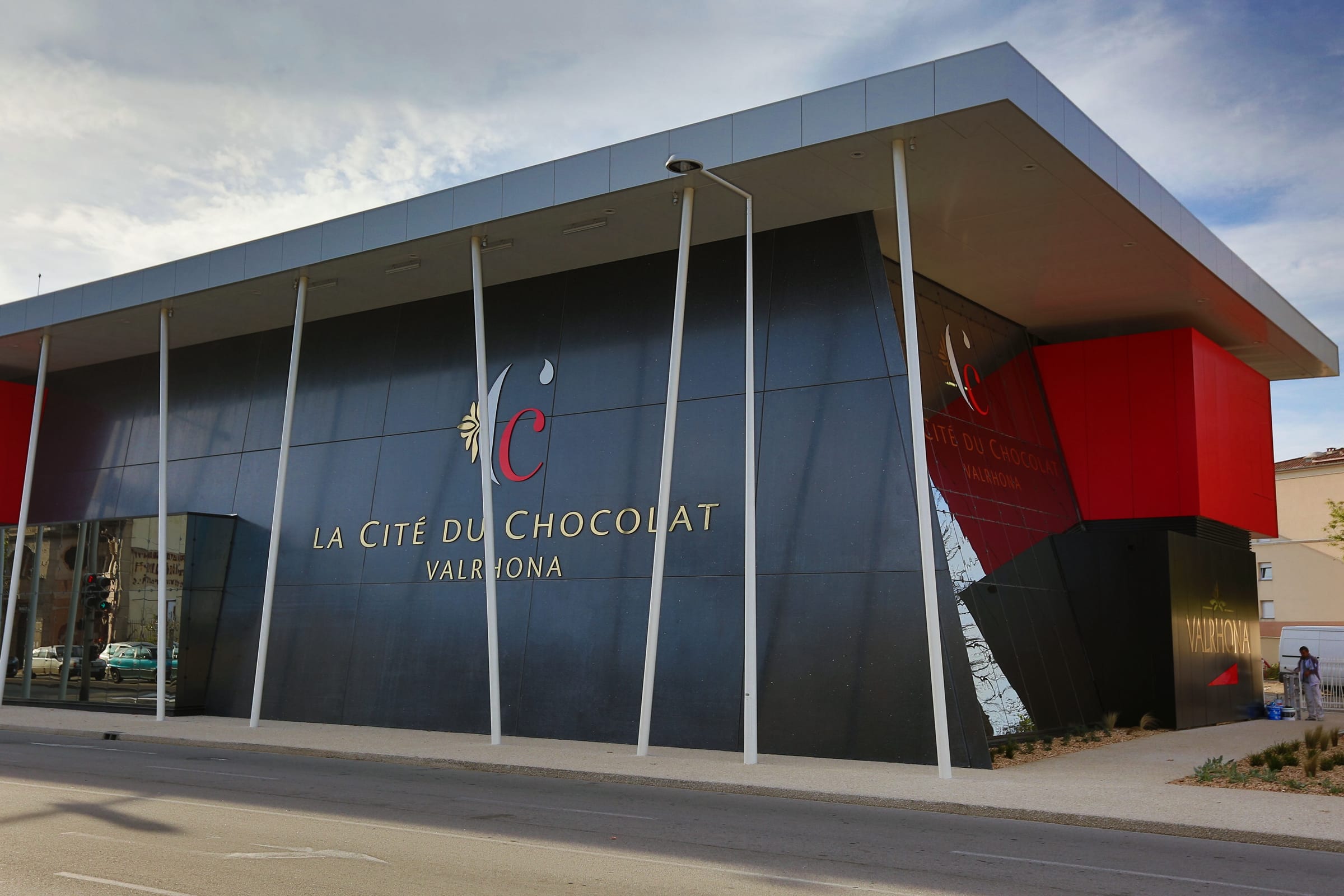 Façade de la Cité du Chocolat Valrhona à Tain-l'Hermitage, bâtiment noir et rouge avec son enseigne
